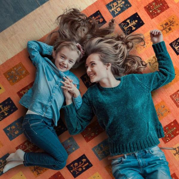 Mother and daughter are laughing on a Persian Gabbeh Loribaft carpet.
