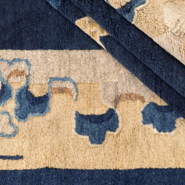 Detailopname van een Chinese Peking antiek tapijt met bloemornamentiek in beige en blauw op donker.