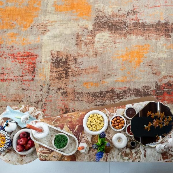 Nowruz table decoration in front of a patterned kilim carpet wall